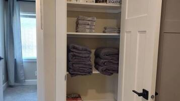 A walk-in closet with shelves, a basket, and folded towels.