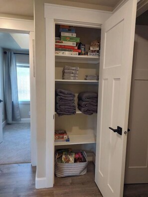 Un dressing avec des étagères, un panier et des serviettes pliées.