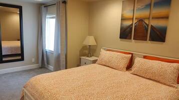 A bedroom with a large bed, a nightstand, a lamp, and a painting on the wall.