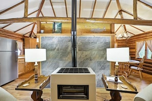 Ein Blockhaus-Interieur mit Kamin, Holzmöbeln und einer Steinsäule.