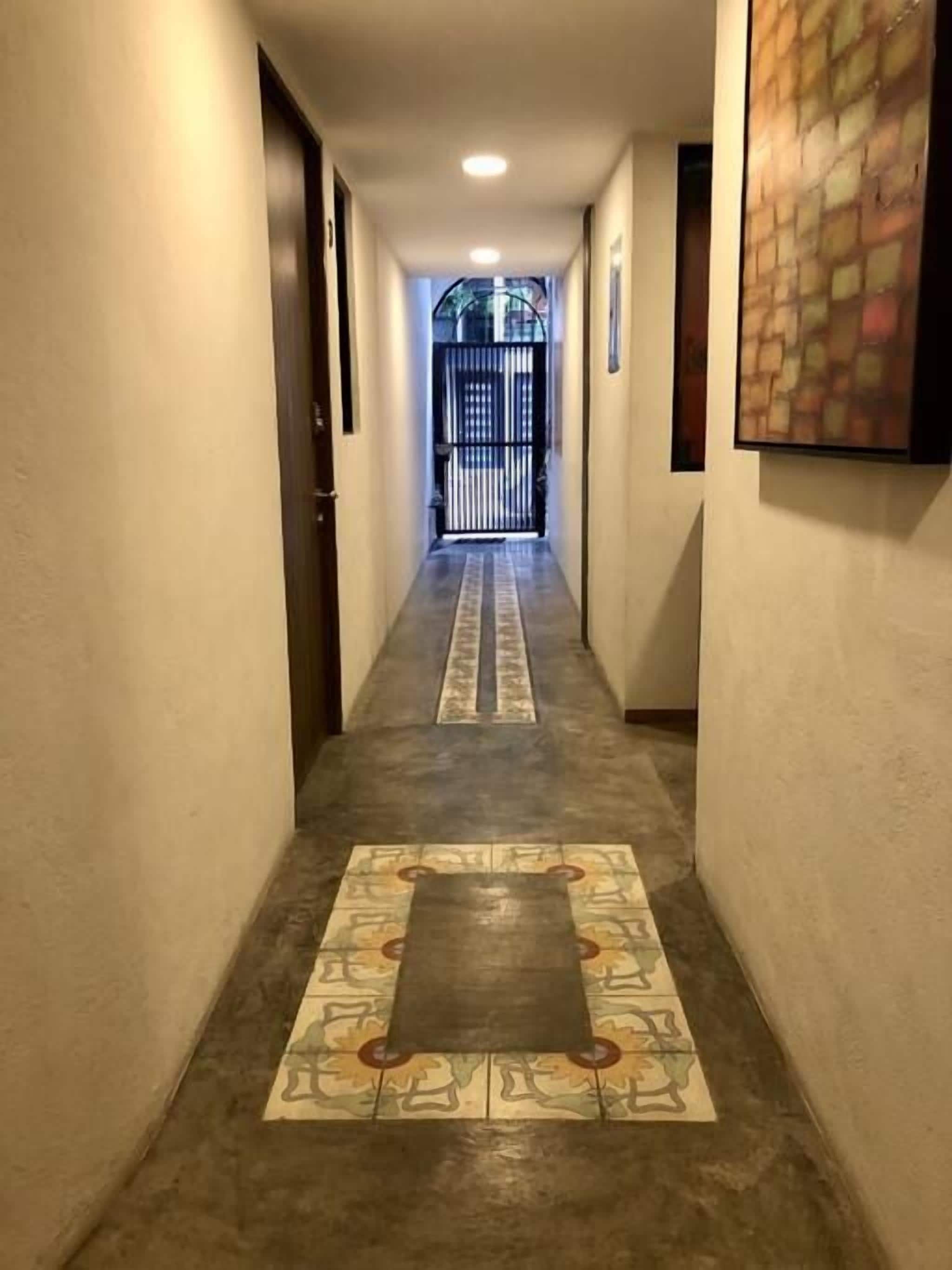 Un pasillo con suelo estampado, una puerta a la izquierda y un portón al final.