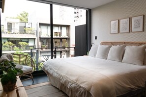 A bedroom with a large bed, a view of the outside balcony, and a few framed pictures on the wall. - Increible Terraza en la condesa (Ciudad de México)