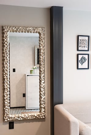 A room with a large mirror, a framed artwork, and a sofa. - Increible y acogedor departamento en la condesa (Ciudad de México)