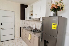 A compact kitchen with a refrigerator, stove, and microwave. - Elegant and Modern Apartment in Bayahíbe | Near the Beach (Bayahíbe)