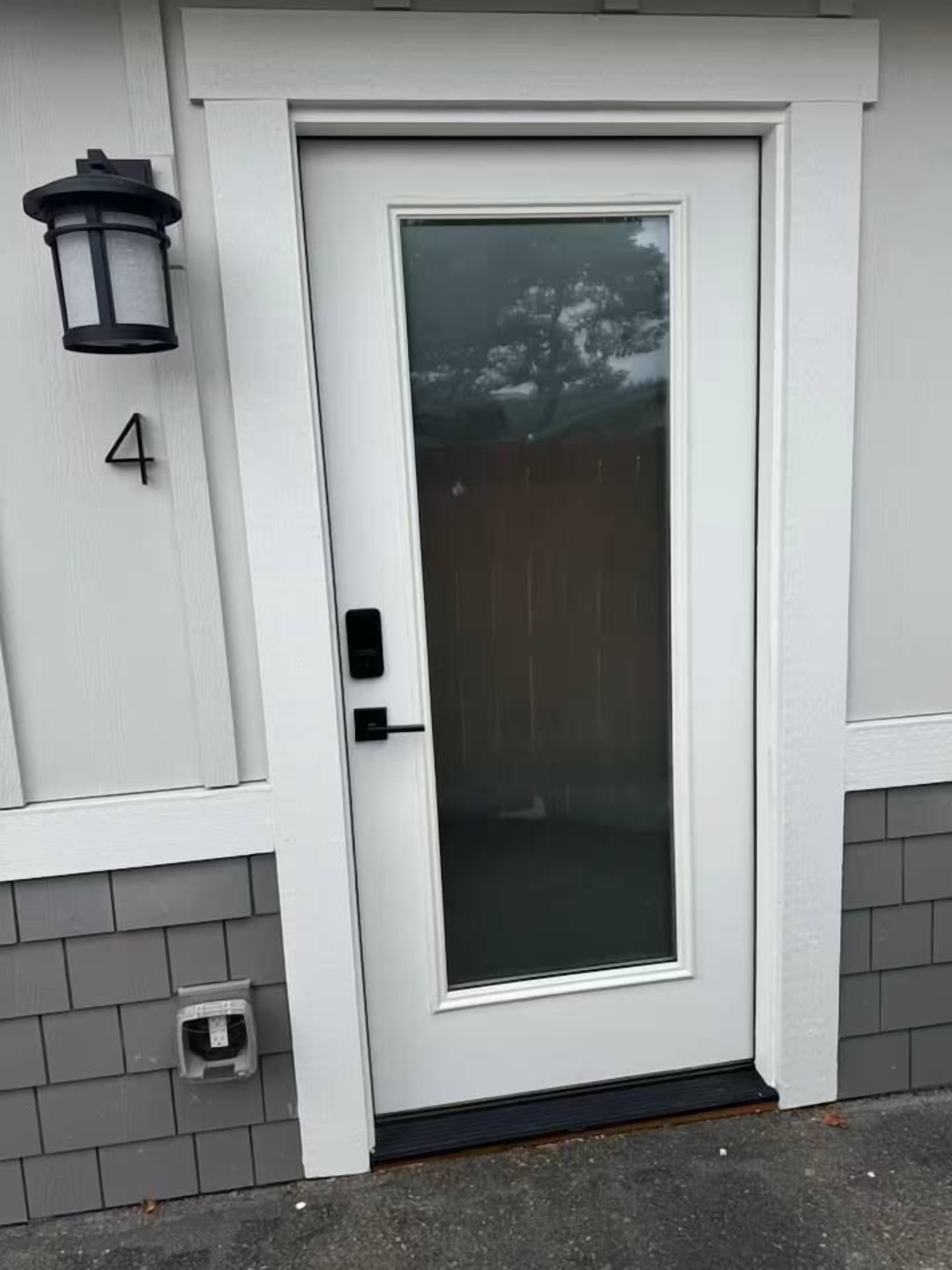 A white door with a glass panel, a black doorbell, and a mailbox on the wall.