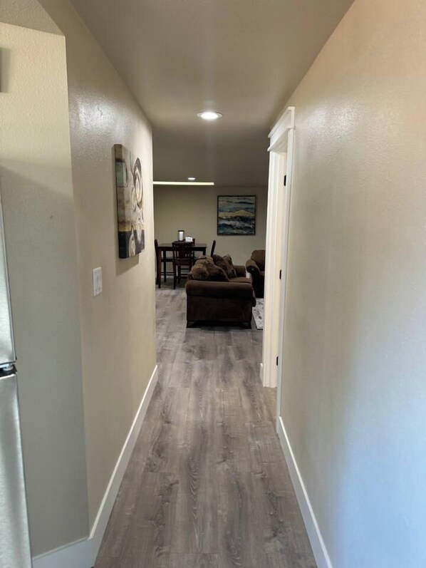 A hallway with a wooden floor leading to a living area with a couch and a painting on the wall. - Fun Florence 2 BR, close to all. Unit 4 (Florence)