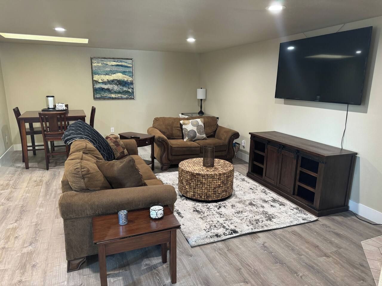 A living room with a sofa, ottoman, coffee table, TV, and a dining area with chairs and a table.