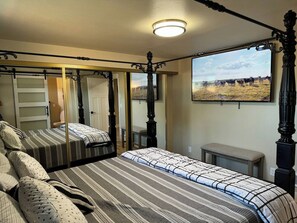 A four-poster bed with a mirror, a bedside table, and a view of a field with cows. - Fun Florence 2 BR, close to all. Unit 4 (Florence)