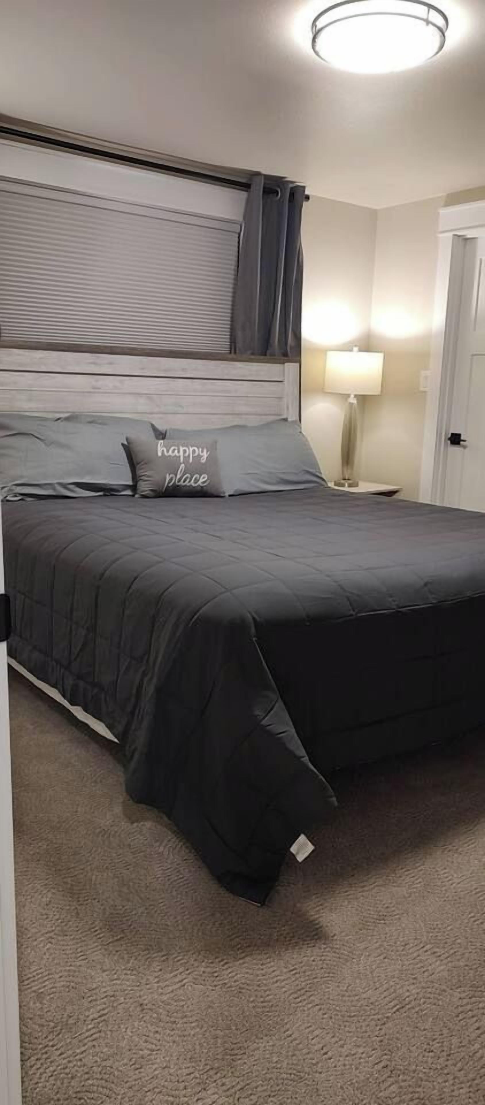 A bedroom with a bed, a headboard, a nightstand, a lamp, and a door.