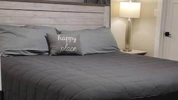 A bedroom with a bed, a headboard, a nightstand, a lamp, and a door.