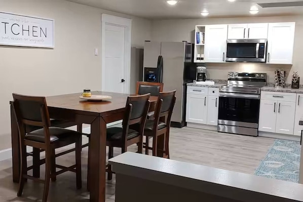 A modern kitchen with white cabinets, stainless steel appliances, and a dining area with a wooden table and chairs. - Old Town Florence Getaway 2 BRM, Unit 1 (Florence)