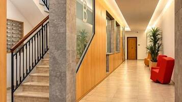 Un hall d’hôtel moderne avec un escalier, un comptoir d’accueil et un fauteuil rouge.