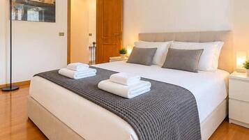 Une chambre d’hôtel moderne avec un grand lit, une table de chevet, une lampe et un tableau encadré au mur.