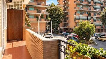 Un balcon avec un mur en briques, une petite porte en bois et une rambarde en métal.