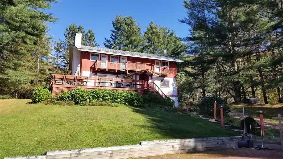 Une cabane en bois à deux étages, dotée d’une terrasse et d’un escalier menant à l’étage supérieur.