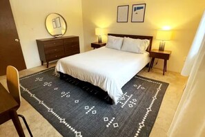 A hotel room with a bed, two bedside tables with lamps, a dresser, a mirror, and a patterned rug. - The Rose Lodge: 8 Bedrooms, 7 Baths, Private Hot Tub and Game Room (Killington)