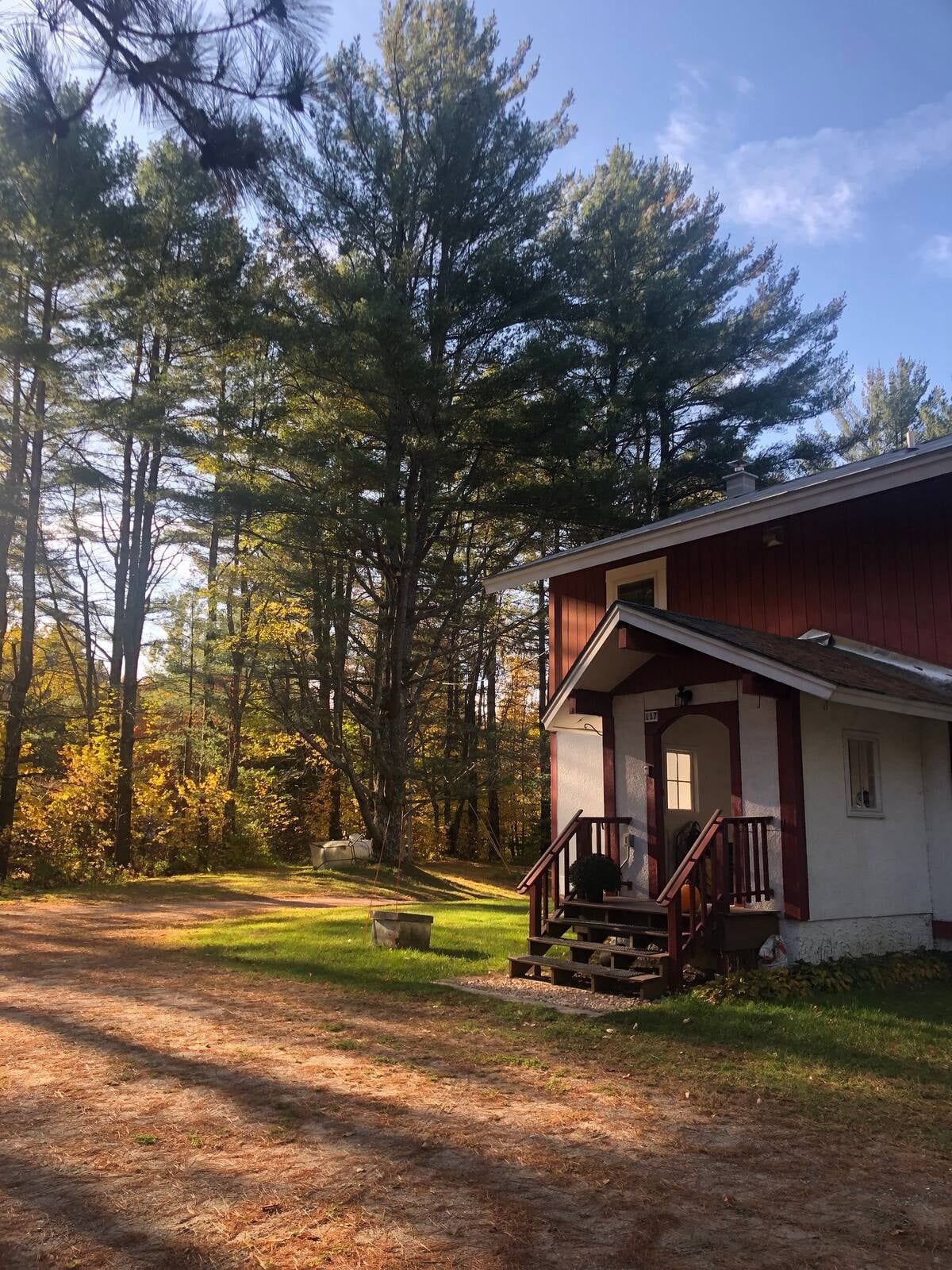 A cabin with a porch, surrounded by trees and a clear sky.