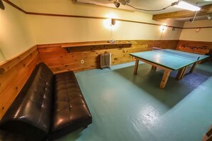 A room with a ping pong table, a bench, and wooden walls. - The Rose Lodge: 8 Bedrooms, 7 Baths, Private Hot Tub and Game Room (Killington)