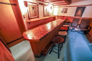 Eine Bar mit einer langen Theke und Hockern, Holzwänden und einem Buddha-Gemälde.