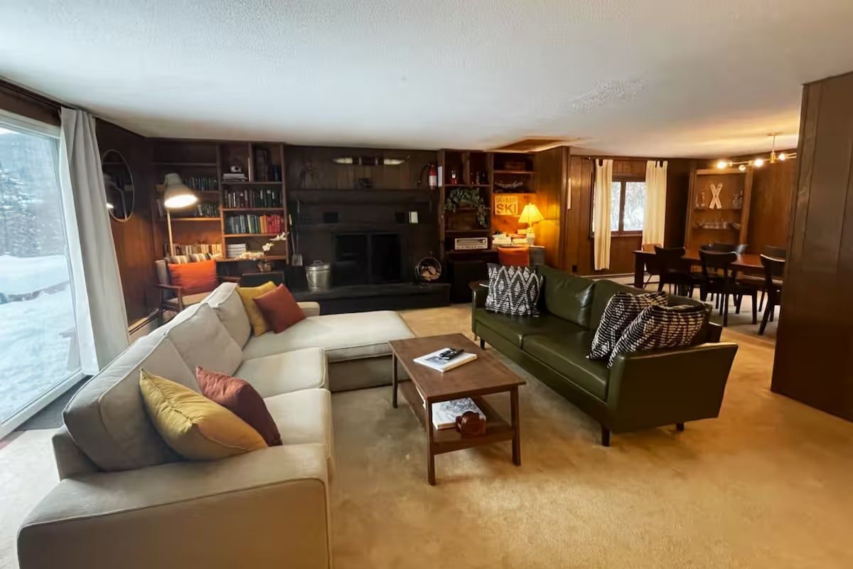 Un salon chaleureux avec une cheminée, un canapé, une table basse et un coin repas.
