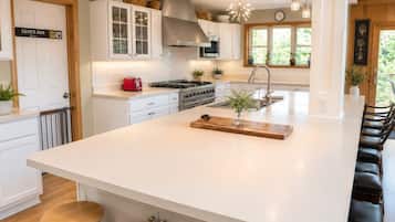 A modern kitchen with white cabinetry, a central island, and bar stools.