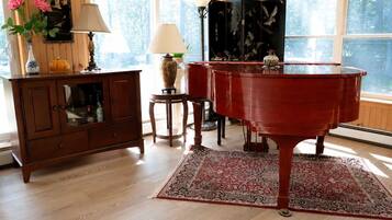 A room with a grand piano, wooden furniture, and a large window.
