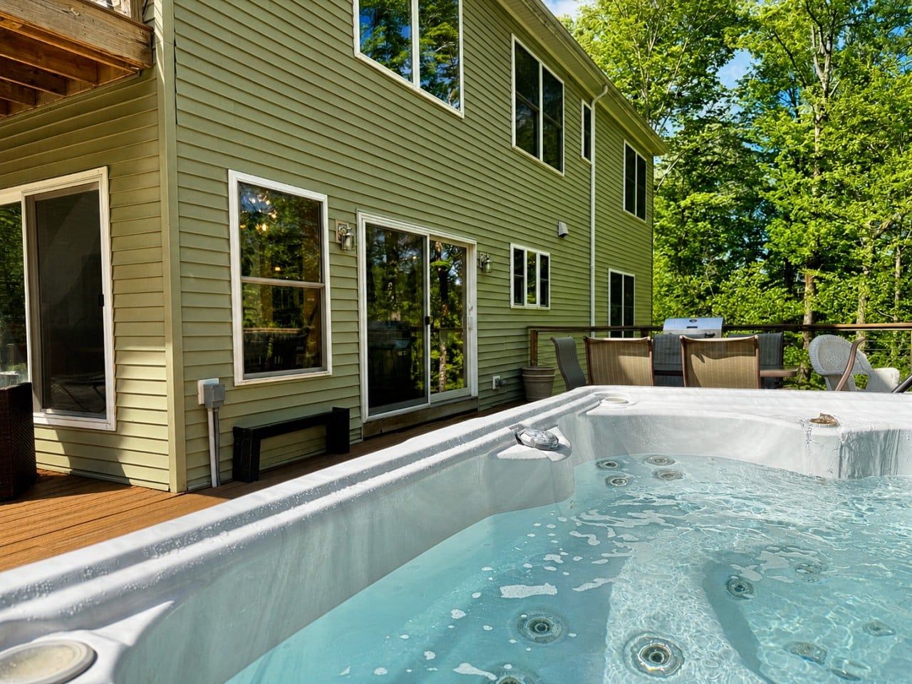 A residential property with a hot tub, outdoor seating, and a deck.