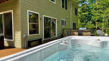 A residential property with a hot tub, outdoor seating, and a deck.
