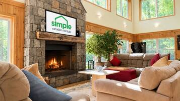 A cozy living room with a stone fireplace, a large window, and a comfortable seating area.