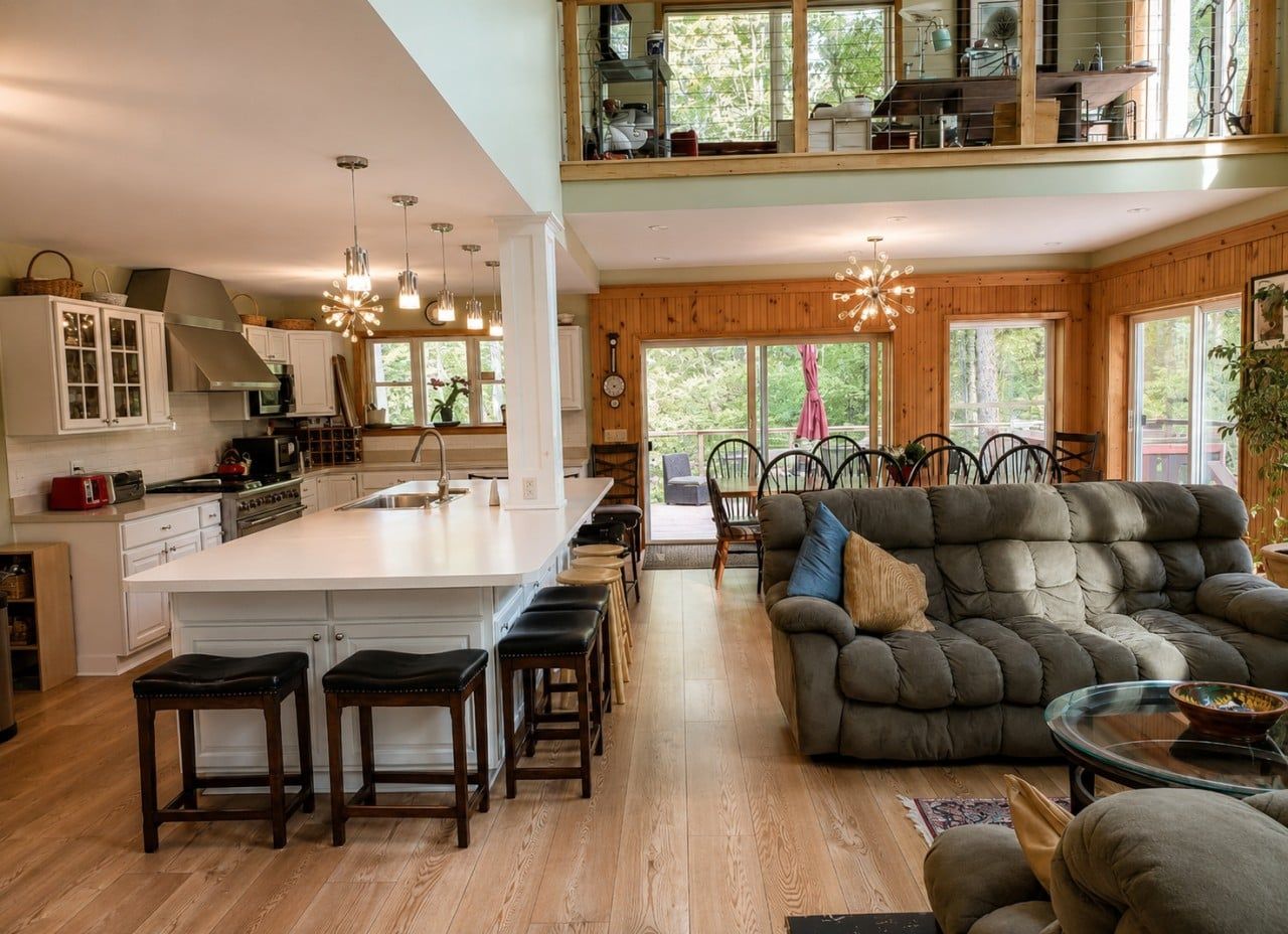 A spacious kitchen with a central island, wooden flooring, and a seating area with a sofa and chairs.