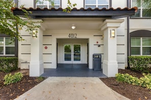 A building entrance with a numbered door, a parking meter, and a small trash bin. - Stay Central, Explore More, Orlando 3BR Condo (Orlando)