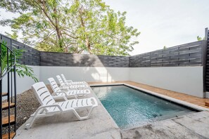 A swimming pool with lounge chairs, surrounded by a low wall and trees. - Cozy 1-bedroom apartment in beautiful Tamarindo with AC (Tamarindo)