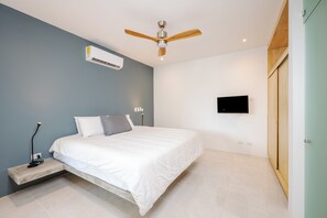 A modern bedroom with a bed, an air conditioning unit, a ceiling fan, a bedside lamp, and a flat-screen TV mounted on the wall. - Cozy 1-bedroom apartment in beautiful Tamarindo with AC (Tamarindo)