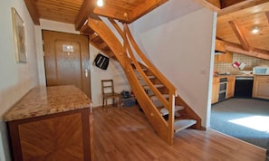A wooden staircase leading to a kitchen area with a wooden countertop and a chair. - IN THE HEART OF ZERMATT,  JUST STEPS FROM THE VILLAGE’S MAIN STREET (Zermatt)