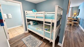 A room with a bunk bed, a dining table with chairs, and a patterned rug. - Shores of Panama 927 - 1 Bedroom+Bunks w/Sunset View (Panama City Beach)