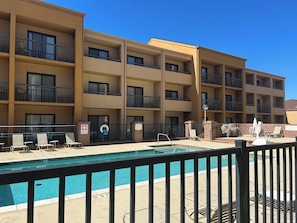 A hotel with multiple balconies, a swimming pool, and outdoor seating. - SureStay (Oklahoma City)
