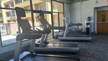 Un gimnasio con cintas de correr, una bicicleta estática y una máquina de pesas.