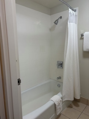A bathroom with a bathtub, a shower, and a white shower curtain. - SureStay (Oklahoma City)