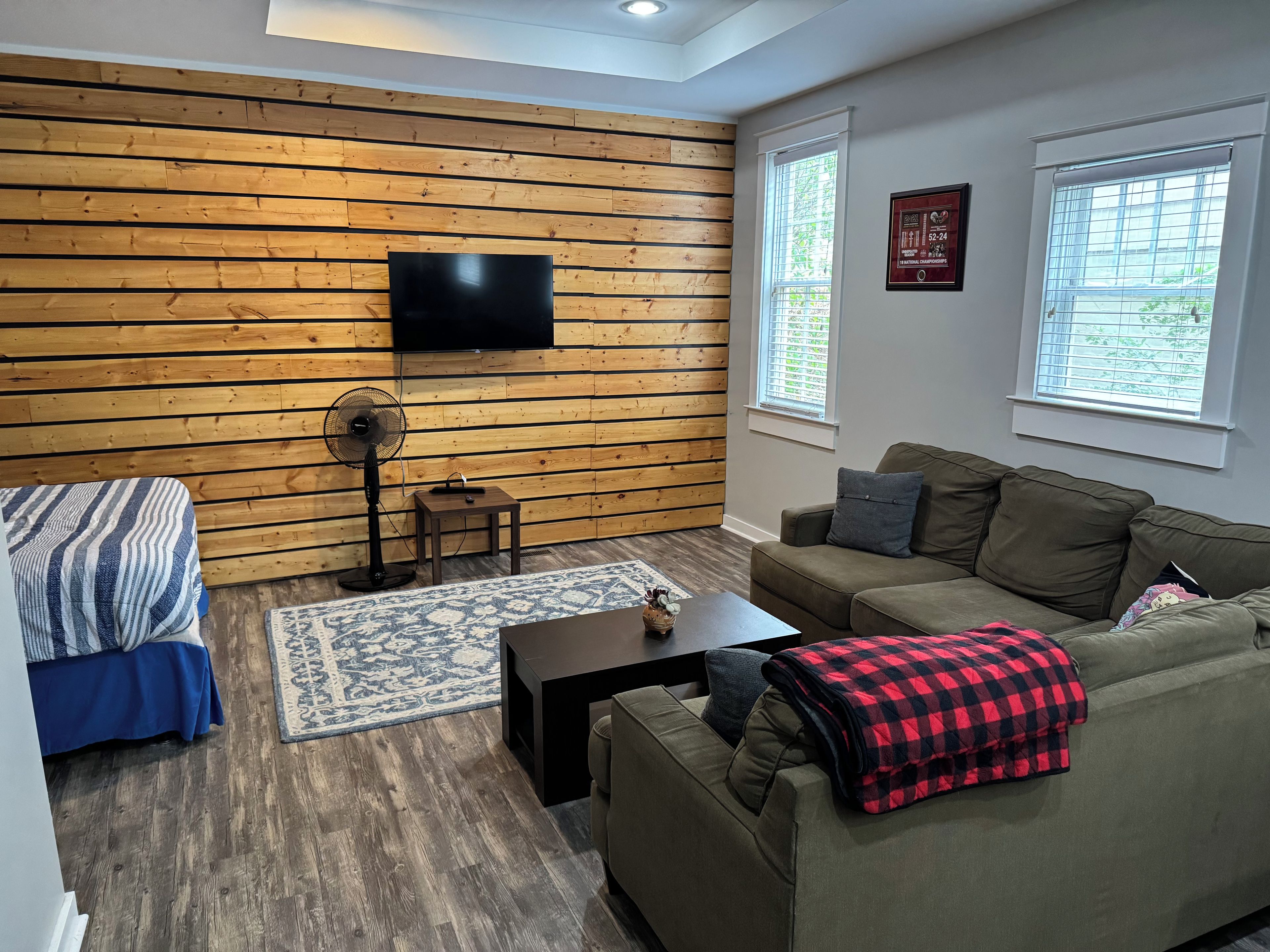 Una sala de estar moderna con un panel de madera, un televisor de pantalla plana, un sofá, una mesita de centro y una pequeña mesita auxiliar.