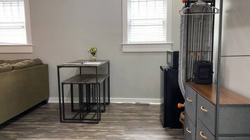A compact living space with a sofa, a small table with a vase, a microwave, and a cabinet with drawers.