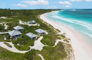 An aerial view of a coastal property with multiple buildings, a sandy beach, and a clear view of the ocean. - Bohemia Cosmo - A Beachfront Bungalow, Pool & Daybed (Governor's Harbour)