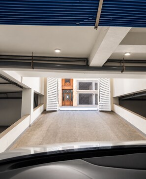 An interior view of a parking garage with a car in the foreground, a door with a decorative design, and a ventilation system on the ceiling. - Cozy apartment 5 minutes from the beach, free parking, fiber-optic Wi-Fi (El Jadida)