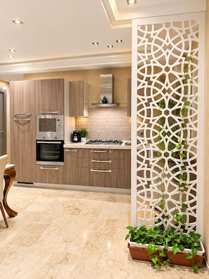 A modern kitchen with built-in appliances, a decorative partition, and potted plants. - Cozy apartment 5 minutes from the beach, free parking, fiber-optic Wi-Fi (El Jadida)