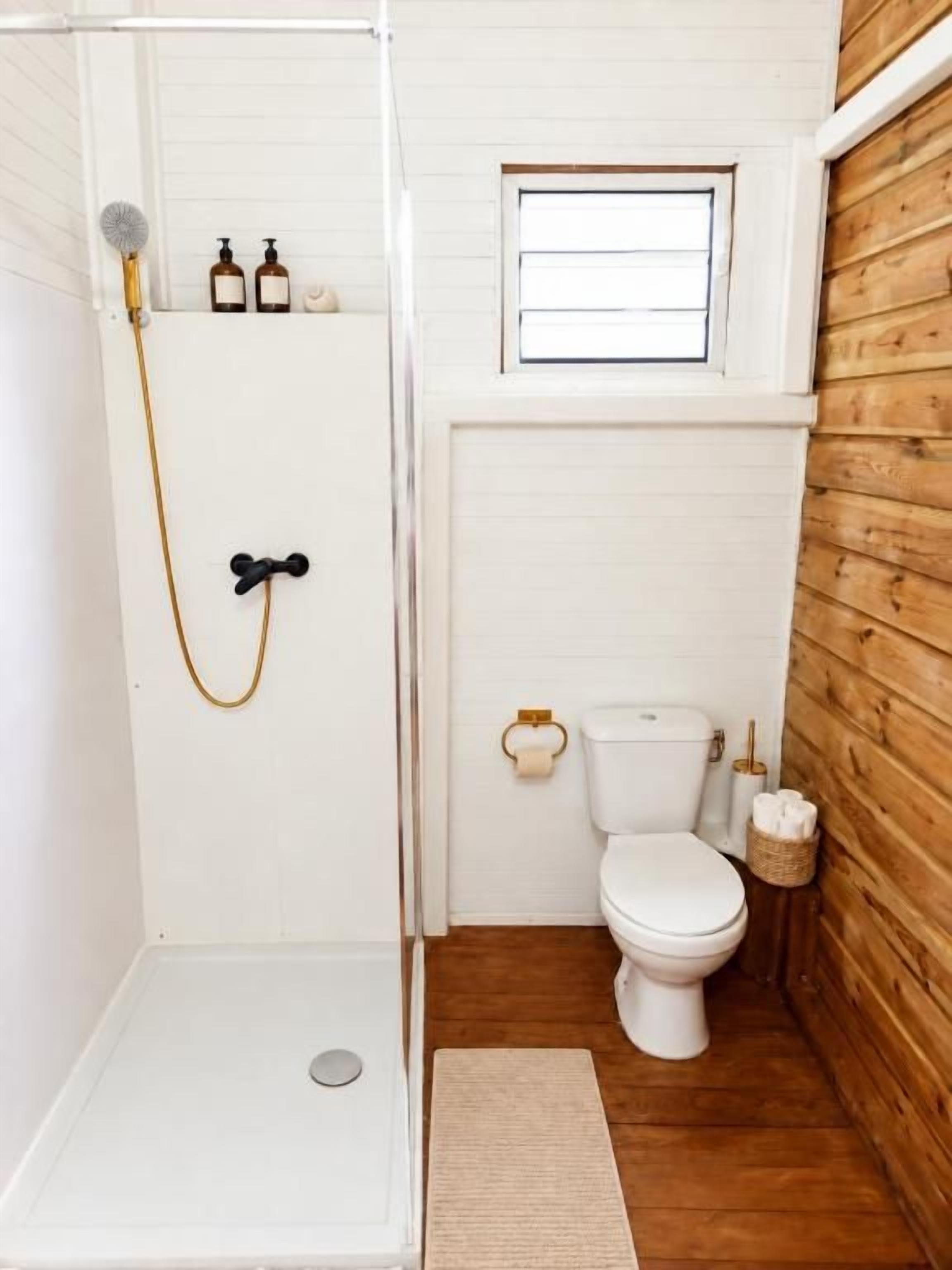 Ein kleines Badezimmer mit Dusche, Toilette und einem Fenster.