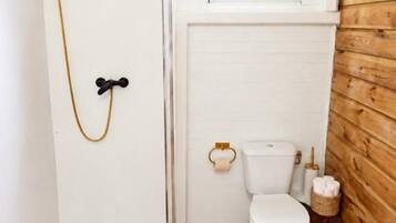 Ein kleines Badezimmer mit Dusche, Toilette und einem Fenster.