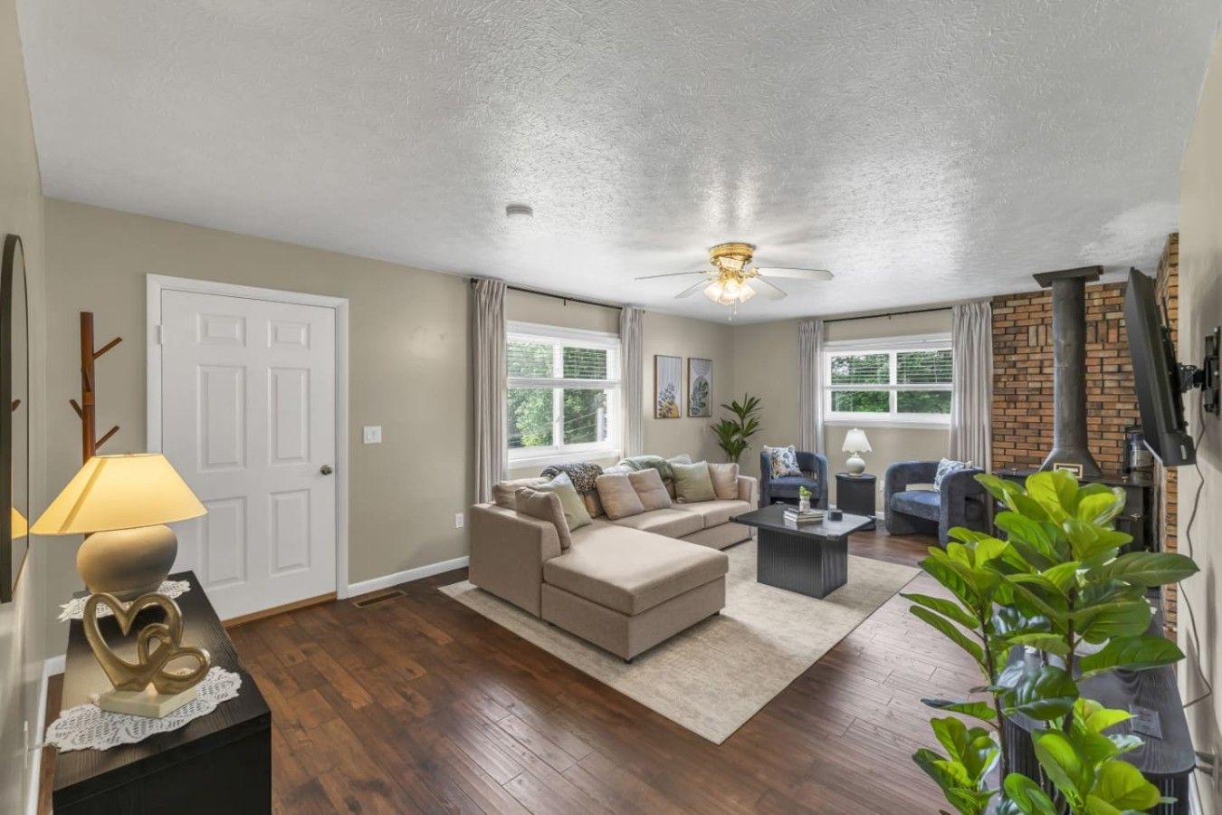 Un salon comprenant un canapé, des fauteuils, une table basse, une cheminée et un ventilateur de plafond.