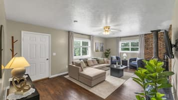 Un salon comprenant un canapé, des fauteuils, une table basse, une cheminée et un ventilateur de plafond.
