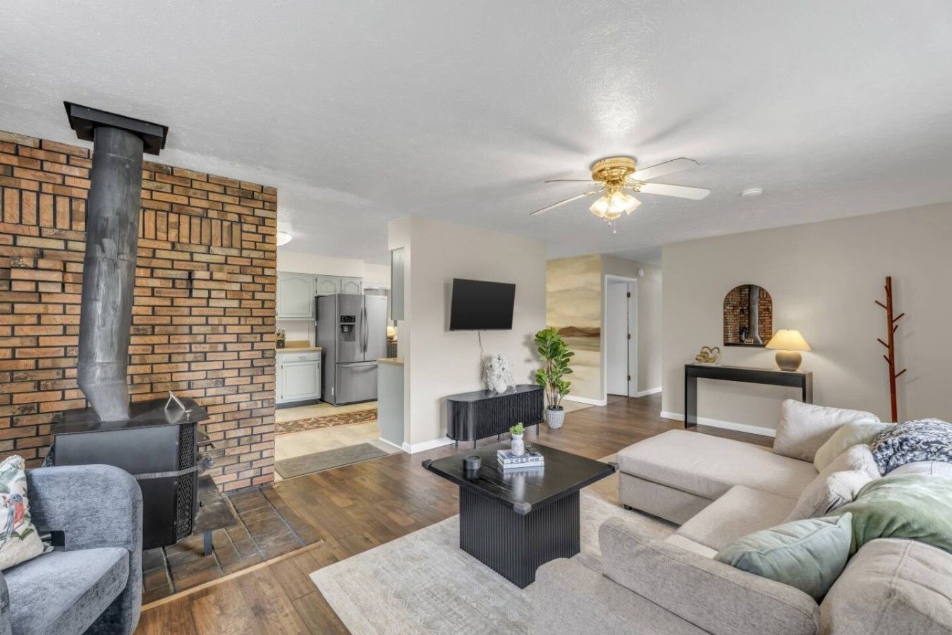 A modern living room with a fireplace, a ceiling fan, and a sofa.