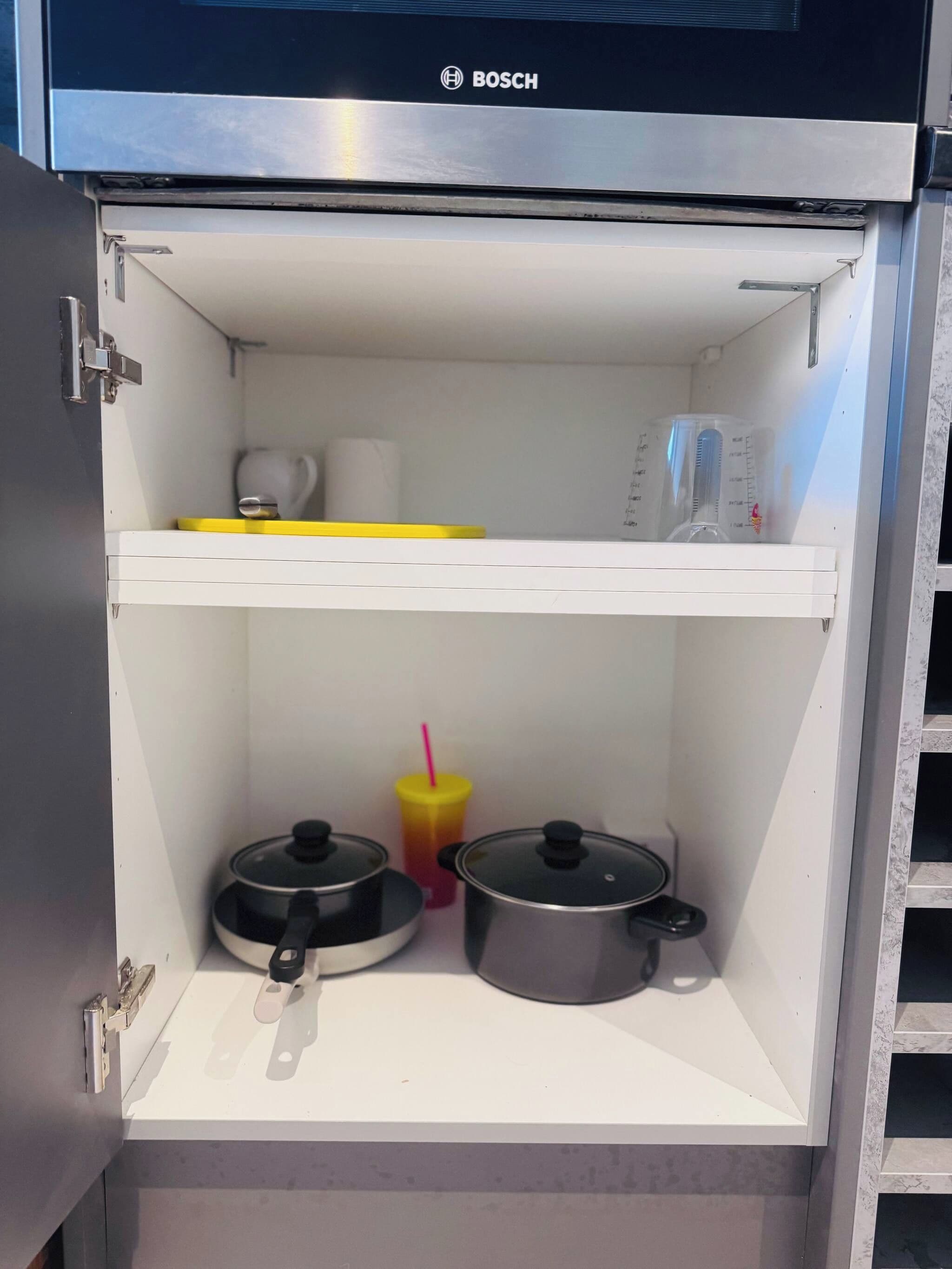 A kitchen with a Bosch appliance, a yellow tray, a pot, a measuring cup, and a cup with a straw.