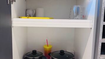 A kitchen with a Bosch appliance, a yellow tray, a pot, a measuring cup, and a cup with a straw.